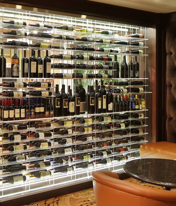 Wood and glass enclosed wine cellar with dramatic label-forward wine bottle storage.